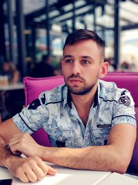 Thoughtful young man sitting at table in restaurant