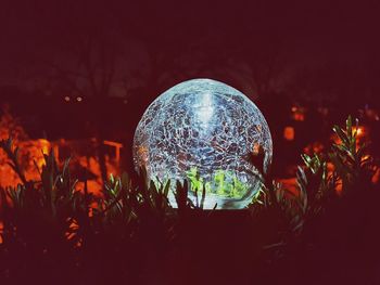 Close-up of illuminated lighting equipment on field at night