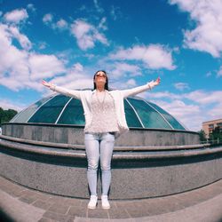 Woman with arms outstretched standing against glass dome