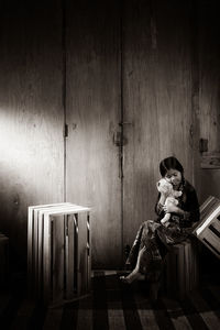 Woman sitting on chair against wall