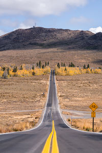 Road amidst field against sky