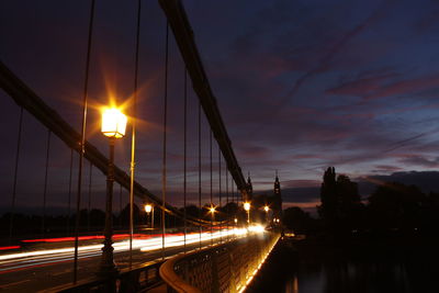 Light trails on bridge in city against sky at night