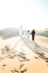 Rear view of family walking on sand dune