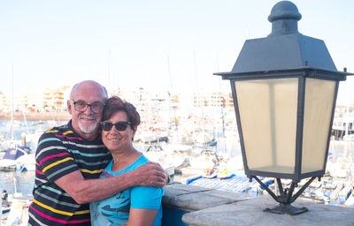 Portrait of smiling senior couple standing by retaining wall