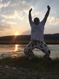 Full length of man standing on land against sky during sunset