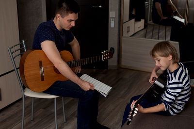 High angle view of instructor teaching guitar to boy