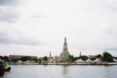 View of buildings at waterfront against cloudy sky