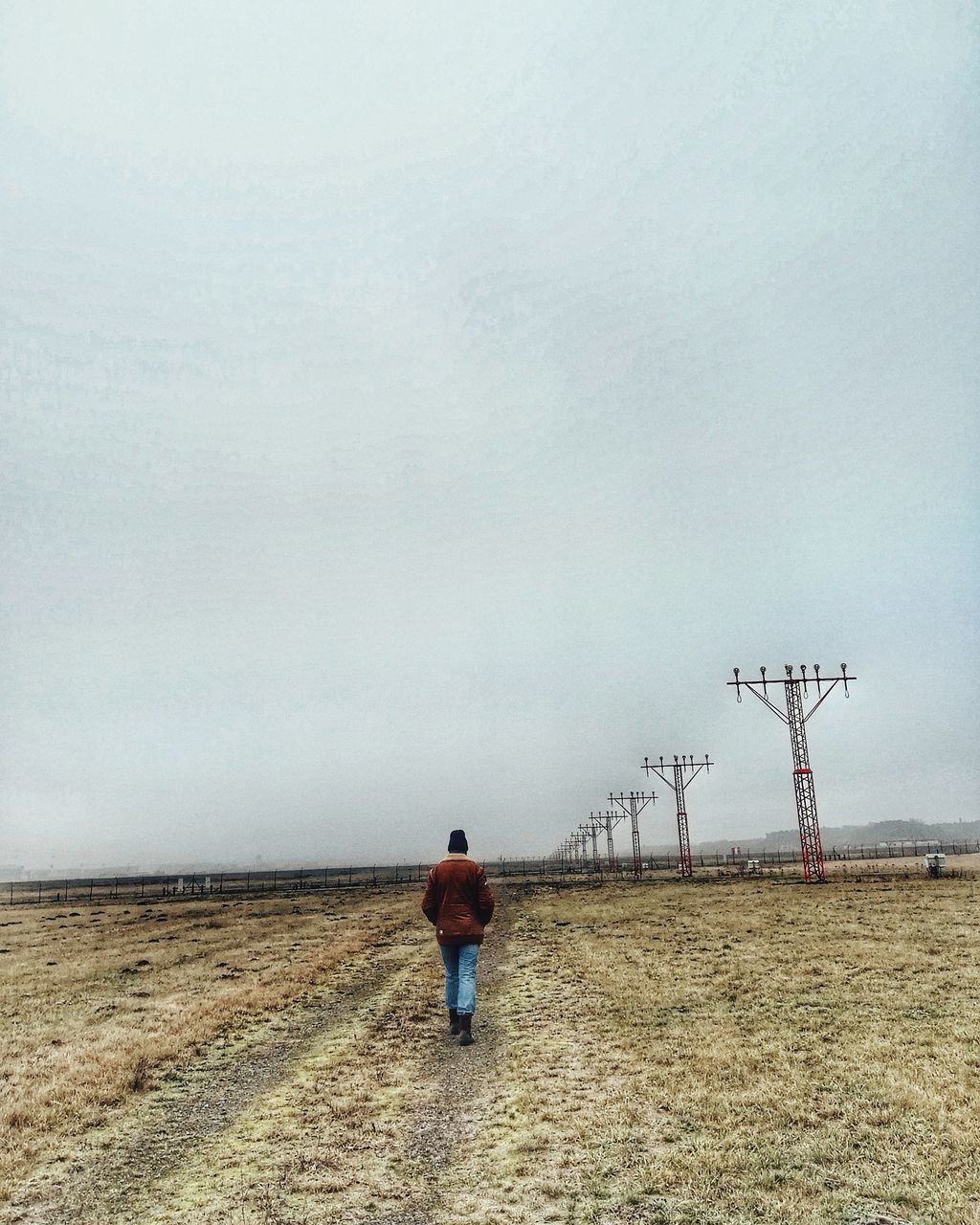 REAR VIEW OF MAN WITH UMBRELLA WALKING ON FIELD