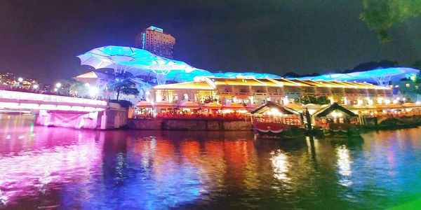 Illuminated building by river at night