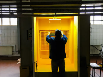 Rear view of man standing against yellow door