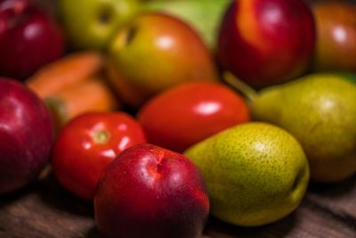 Close-up of apples with tomatoes and pears on table