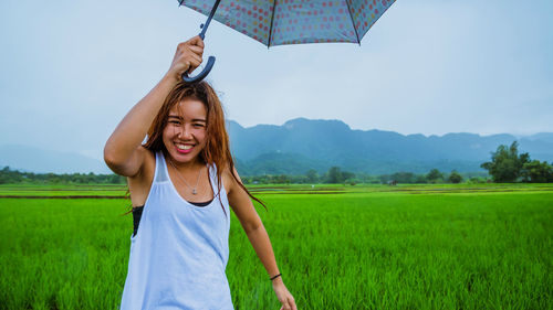 Portrait of woman with umbrella standing on field