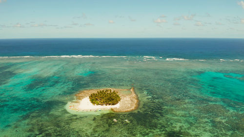 Sandy beach on a small island by coral reef atoll from above. guyam island