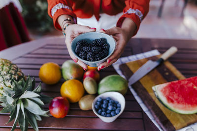 Midsection of woman holding fruits on table