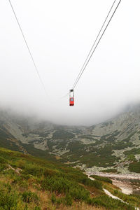 Overhead cable car over mountains during foggy weather