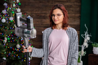 Portrait of young woman standing by christmas tree