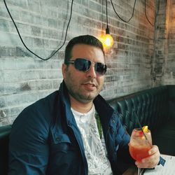 Portrait of man holding juice while sitting on sofa