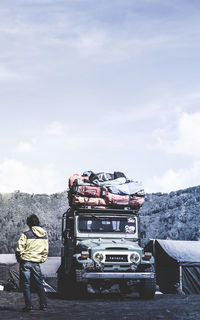 Rear view of man standing on truck against sky