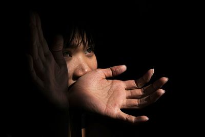 Close-up of woman looking away against black background