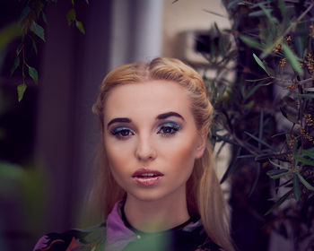 Portrait of beautiful young woman against plants