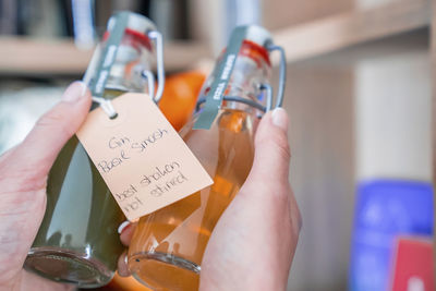 Closeup of tourist holding flavored gin bottles with tag at hotel room