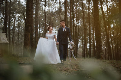 The newlyweds happy in the atmosphere of the pine forest, looking and feeling warm.