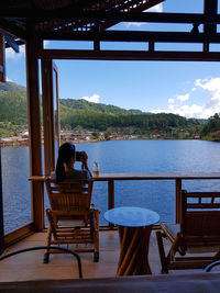 Woman relaxing on table by sea against sky