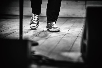 Low section of man wearing canvas shoes walking on floorboard