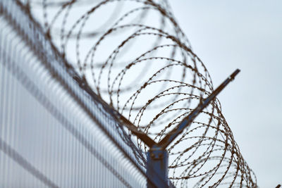 Low angle view of barbed wire against sky