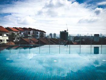 Swimming pool by buildings in city against sky