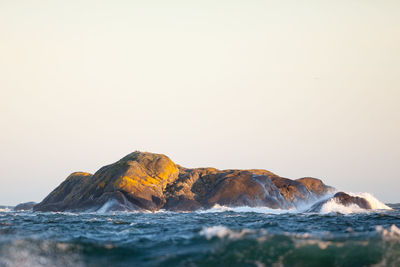 Surface level view of rock formations amidst sea against clear sky