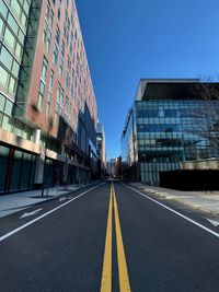 Road by buildings against sky in city