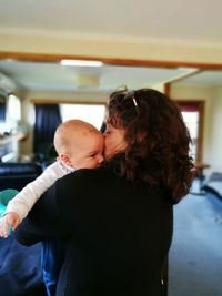 Mother carrying son while standing at home