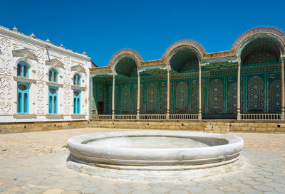 Fountain in front of building against blue sky