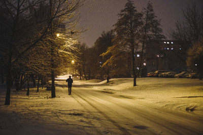 Man walking on snow covered road at night