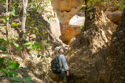 Rear view of man standing amidst rock