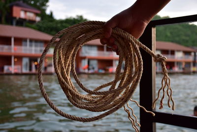 Close-up of person holding rope against railing