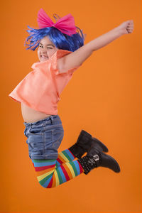 Low angle view of woman against orange background