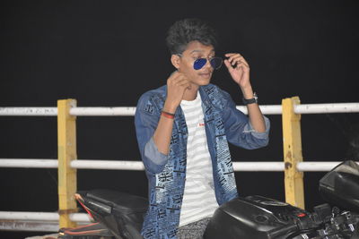 Portrait of man wearing sunglasses standing against railing