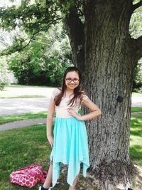 Portrait of a smiling young woman standing on tree trunk