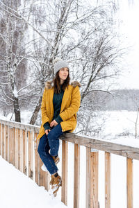 Full length of woman on snow covered bare tree