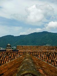 Panoramic view of roof and mountains against sky