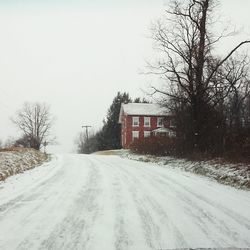 Road by house against clear sky during winter