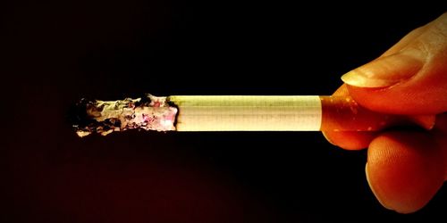 Close-up of man smoking against black background