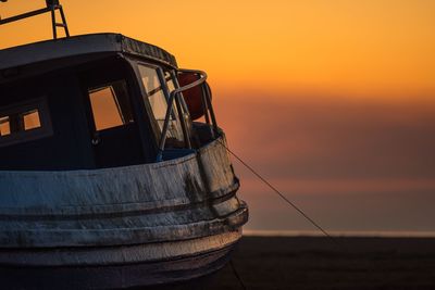 Close-up of boat moored in sea against sky during sunset