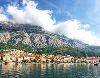 Scenic view of townscape by mountains against sky