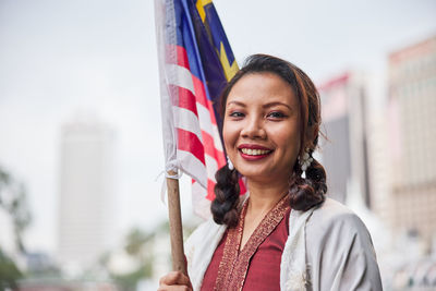 Portrait of young woman holding american flag