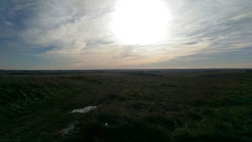 Scenic view of grassy field against cloudy sky