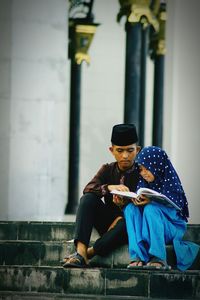 Boy assisting sister for studying while sitting on steps