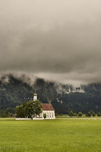 Built structure on field by buildings against sky